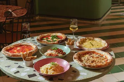 a table with several pizzas and glasses of wine at CASA MOVIDA HOSTEL in Cartagena de Indias
