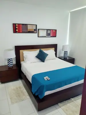 a bedroom with a bed with a blue blanket and two lamps at Morros 922 una alcoba Edificio frente al mar in Cartagena de Indias