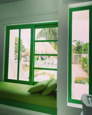a window with a green window seat with a view of a patio at Bahia Tropical Sandia Kiwi Piña in Coveñas