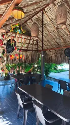 a restaurant with tables and chairs under a straw roof at Anuk Glamping in San Bernardo del Viento
