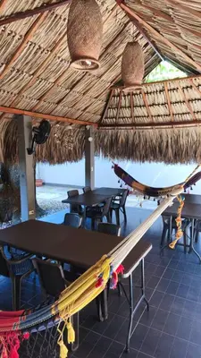a table and chairs under a straw roof at Anuk Glamping in San Bernardo del Viento