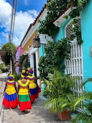three women in colorful dresses walking down a street at Casa Renacer in Cartagena de Indias