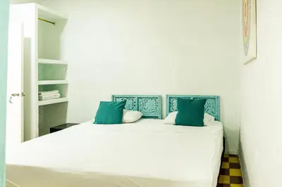 a bedroom with a white bed with blue pillows at Casa Renacer in Cartagena de Indias