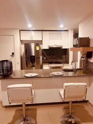 a kitchen with white cabinets and two bar stools at MORROS EPIC luxury beach in Cartagena de Indias