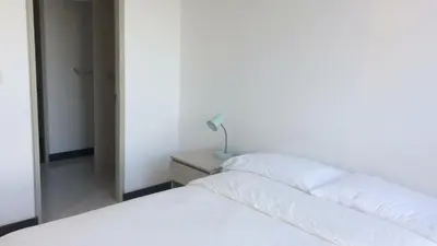a bedroom with a white bed and a lamp on a night stand at Hermoso Apto con vista a la sierra y a Cabo Tortuga en el sector del Irotama en Santa Marta in Gaira
