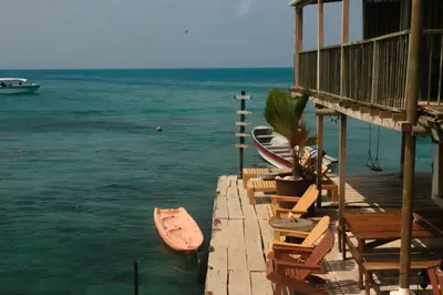 a dock with chairs and a boat in the water at Hostel Santa Cruz del Islote in Santa Cruz del Islote
