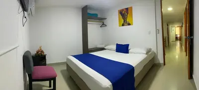 a bedroom with a blue and white bed and a pink chair at Hotel ITACO in Cartagena de Indias