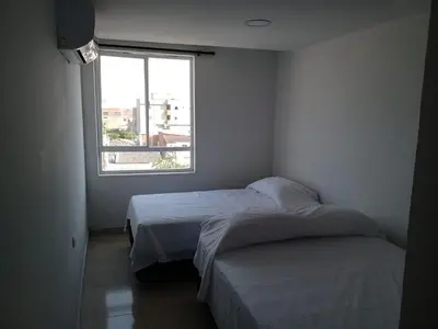 two beds in a small room with a window at HOTEL BOSQUE DE LAS AMERICAS in Cartagena de Indias
