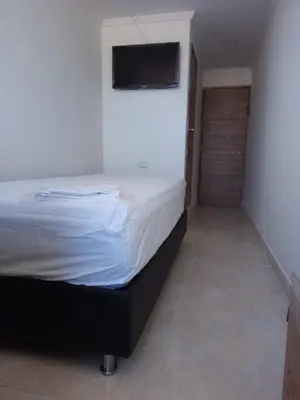 a bedroom with a bed with a television on the wall at HOTEL BOSQUE DE LAS AMERICAS in Cartagena de Indias
