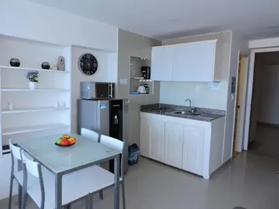 a kitchen with white cabinets and a table with a bowl of fruit on it at Estudio Loft Cartagena in Cartagena de Indias