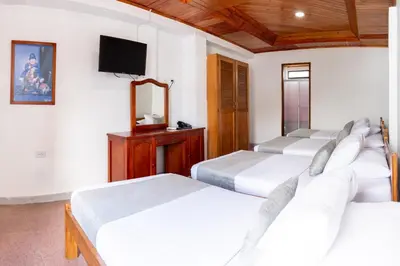 a bedroom with four beds and a tv on the wall at Hotel Corozal Plaza in Corozal