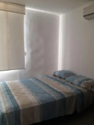 a bedroom with a bed with blue sheets and a window at Rincon 94- Barranquilla- Rio Alto in Barranquilla