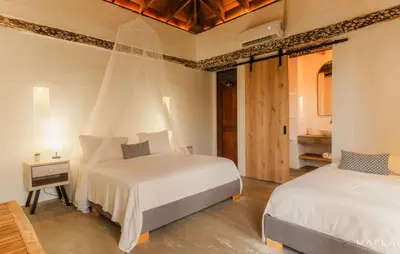 a bedroom with two beds and a room with a dresser at Rosario EcoHotel - Islas del Rosario in Isla Grande