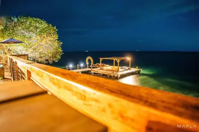 a wooden dock in the water at night at Rosario EcoHotel - Islas del Rosario in Isla Grande