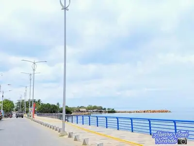 a street with a blue fence next to the water at Hotel El Puerto in Tolú