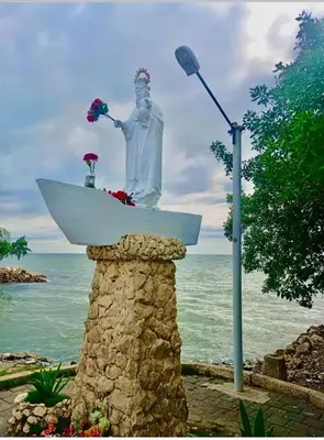 a statue of a man in a surfboard on the ocean at Hotel El Puerto in Tolú