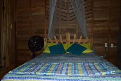 a bed with blue and yellow pillows in a room at Palmar del viento cabaña frente al mar in Moñitos