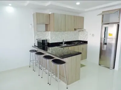 a kitchen with a counter with stools and a refrigerator at Cristoforo Oasis in Cartagena de Indias