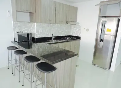 a kitchen with a counter with bar stools and a refrigerator at Cristoforo Oasis in Cartagena de Indias