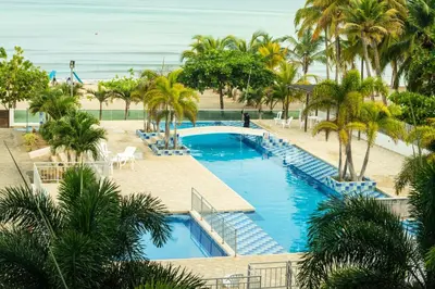 an aerial view of a resort pool with palm trees and the ocean at Magico Apartamento Frente al Mar 3 Habitaciones AR33 in Coveñas