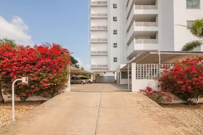 a sidewalk in front of a building with red flowers at Magico Apartamento Frente al Mar 3 Habitaciones AR33 in Coveñas
