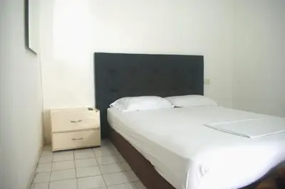 a bedroom with a white bed with a black headboard at Mango Tree Hostel CTG 420 in Cartagena de Indias