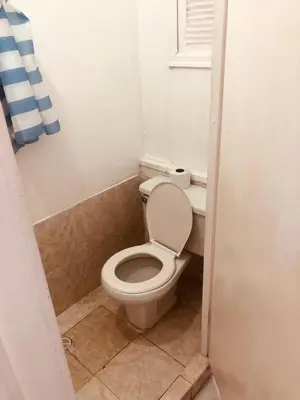 a small bathroom with a toilet and a window at Tita’s Airport Hotel in Cartagena de Indias