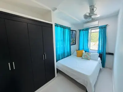 a bedroom with blue curtains and a bed and a window at Cabana Costa Azul in Coveñas