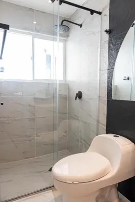 a bathroom with a toilet and a glass shower at Apartamento en Bocagrande - Piscina, Jacuzzi y Mar in Cartagena de Indias