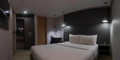 a hotel room with a white bed with a black headboard at The Blue Hotel in Cartagena de Indias