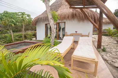 a patio with two lounge chairs and a house at AMALIFE Beach Club & Hotel in Tierra Bomba