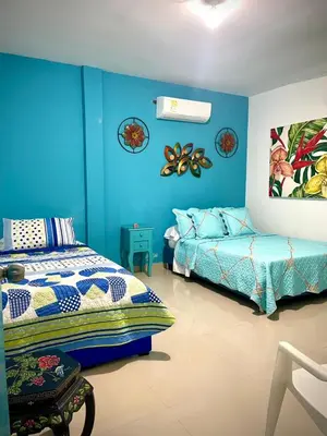 a bedroom with blue walls and a bed and a couch at San José Beach in Lomarena