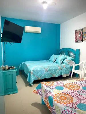 a blue bedroom with two beds and a tv at San José Beach in Lomarena