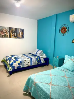 a bedroom with two beds and blue walls at San José Beach in Lomarena