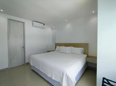 a bedroom with a white bed and a door at Atlantis Suites -Amoblados Nuevos sector Buenavista in Barranquilla