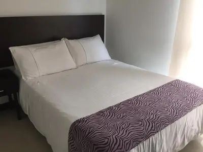 a bed with a black and white comforter and pillows at Atlantis Suites -Amoblados Nuevos sector Buenavista in Barranquilla