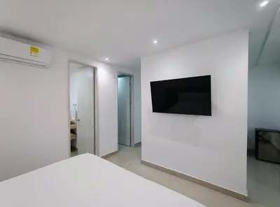 a white bedroom with a tv on a white wall at Atlantis Suites -Amoblados Nuevos sector Buenavista in Barranquilla