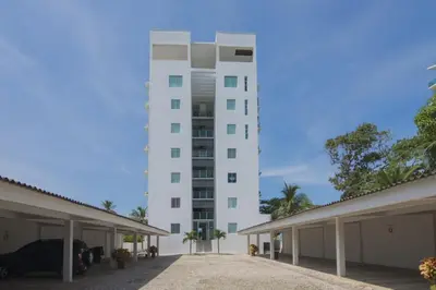 a tall white building with a parking lot at Magico Apartamento Frente al Mar 2 Habitaciones B22B in Coveñitas