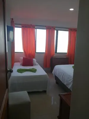 a bedroom with two beds and windows with red curtains at Vista al mar en Edificio Mar Adentro Bocagrande in Cartagena de Indias