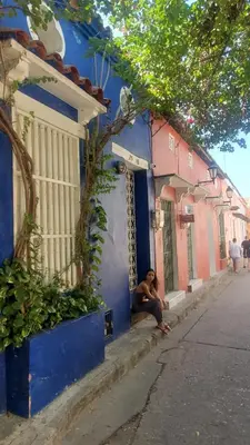 a man sitting on the side of a blue building at Casa Azulita RNT# 64888 in Cartagena de Indias