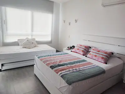 a white bedroom with two beds and two windows at Spiaggia di Cartagena primera línea de playa in Cartagena de Indias