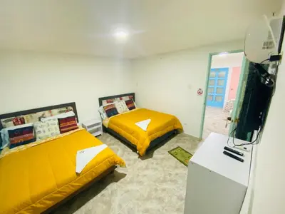 a bedroom with two beds and a refrigerator at House Marfito Airport in Cartagena de Indias