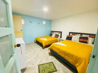 two beds in a room with yellow sheets at House Marfito Airport in Cartagena de Indias