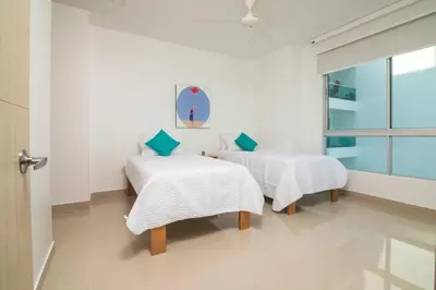 a room with two beds with white sheets and blue pillows at Magico Apartamento Frente al Mar 3 Habitaciones AR91 in Pativilca