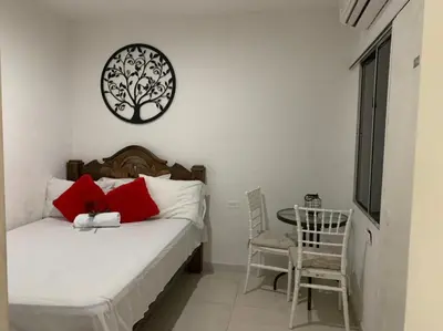 a bedroom with a bed with red pillows and a table at Hostal Marbella 47 in Cartagena de Indias