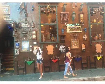 two people walking in front of a bar at III NICE 2 BEDROOM APARTMENT Bocagrande in Cartagena de Indias
