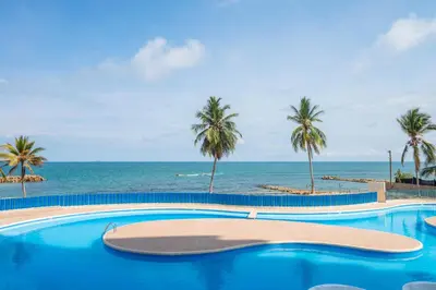 a swimming pool with palm trees and the ocean at Hermoso Apartamento Frente al Mar 2 Habitaciones PAZ148 in Coveñitas