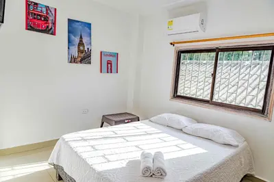 a bedroom with a bed with white sheets and a window at Luna Cartagena Airport Hotel in Cartagena de Indias