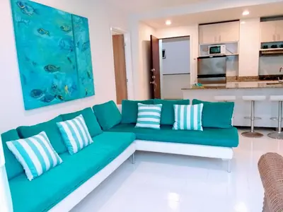 a living room with a green couch and a kitchen at Cartagena primera línea de playa azul frente al mar in Cartagena de Indias