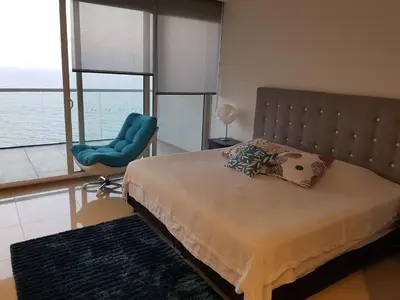 a bedroom with a bed and a blue chair at H2 Hyatt Vista Mar!! in Cartagena de Indias